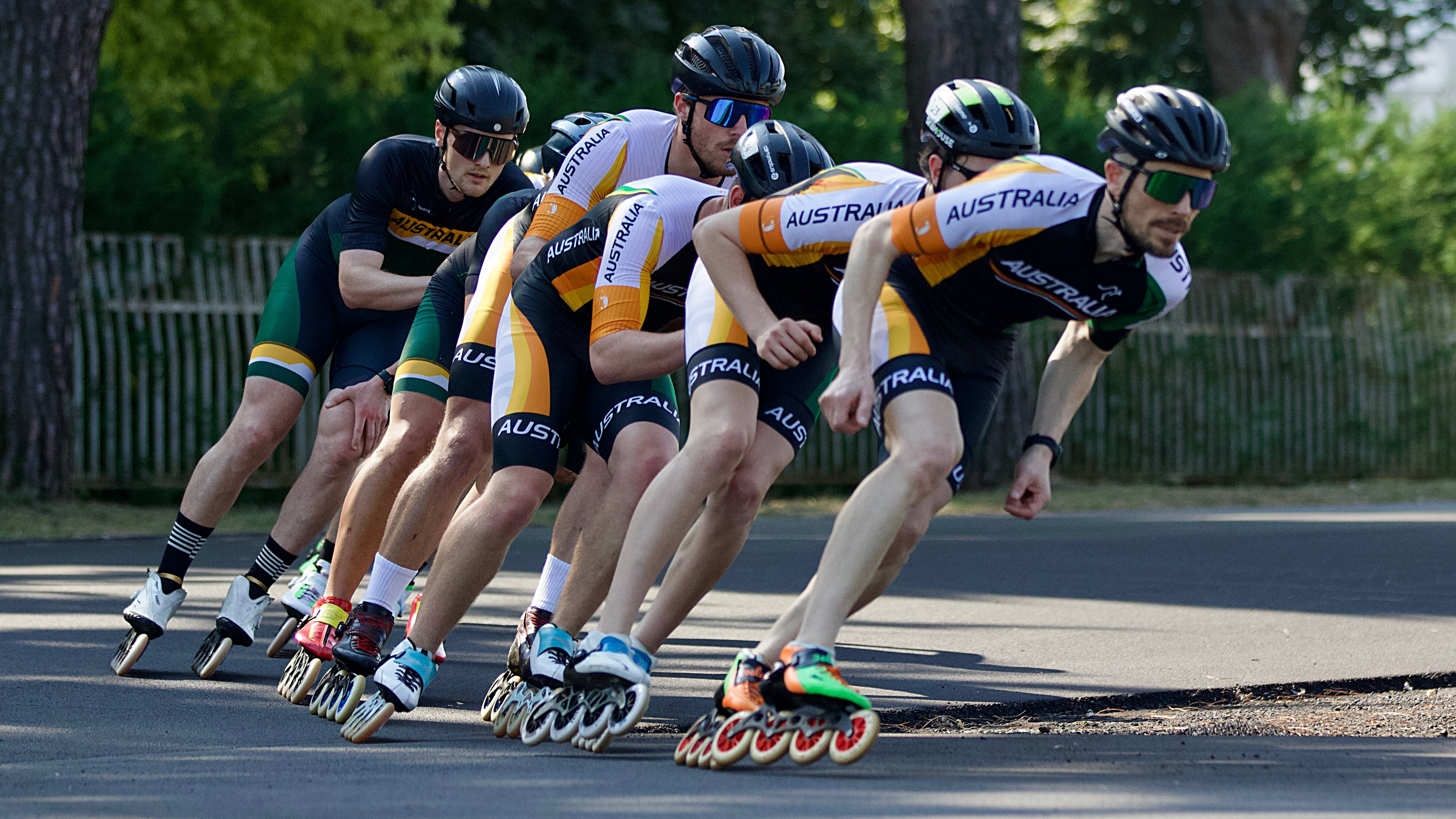 Speed skaters cornering in a tight group outdoors