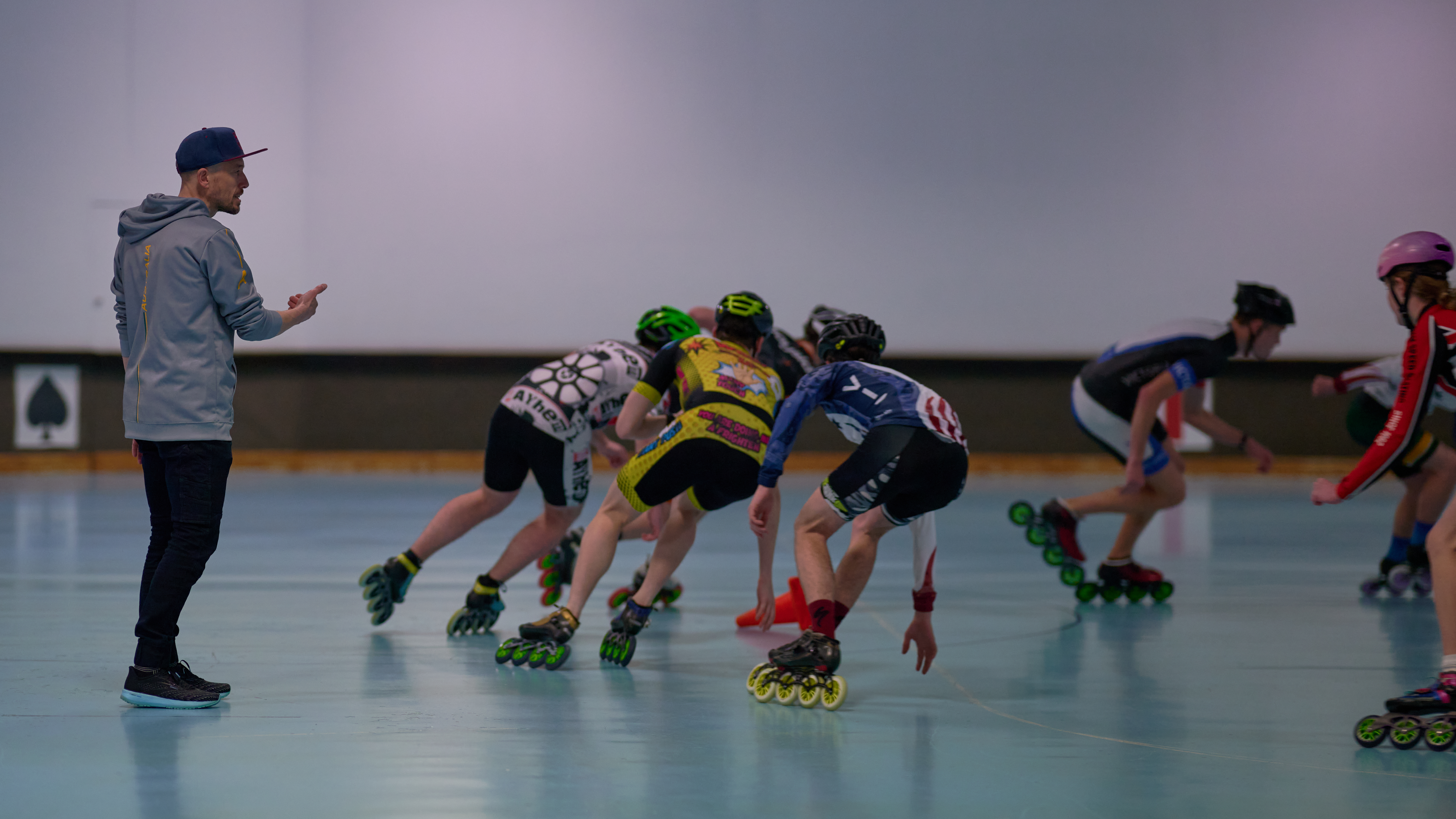 Speed skating coach and skaters practicing indoors